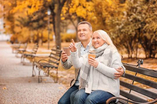 Happy mature couple resting on bench in park