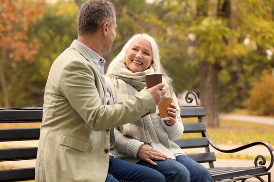 Happy mature couple resting on bench in park