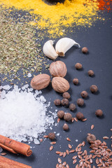 Natural spices and herbs scattered on dark background. Natural and bio ingredients for cooking. Organic products. Copy space for your text.