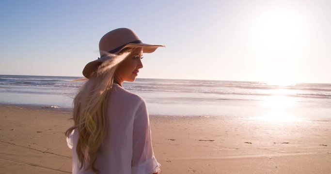Attractive blond woman walking on the beach at sunset. Slow Motion.