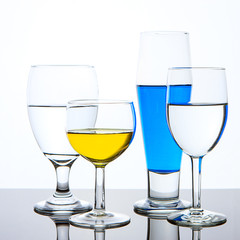 Clear and colored liquid in glasses.