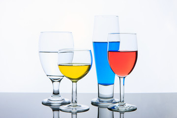 Glasses with red, yellow, and blue water.