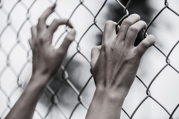 Woman hand holding on chain link fence for remember Human Rights Day concept.