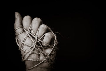 a woman hand tied with wire on dark background in low key. international human rights day concept.
