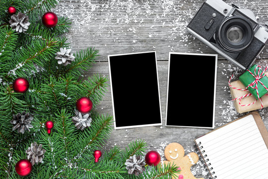 retro camera and christmas blank photo frames with fir tree branches, decorations, gift boxes and lined notebook