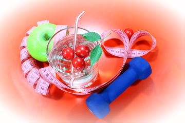 A green apple with a measuring tape. A delicious home made drink with fresh berries in a glass. Healthy breakfast, on a colorful red background in a healthy diet concept and diet, vignette