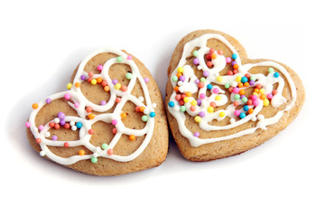 isolated on white background two heart shape gingerbread cookies decorated with icing and confectionery powder with copy space