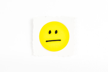 Yellow expressionless face emoji note message on white background paper desk
