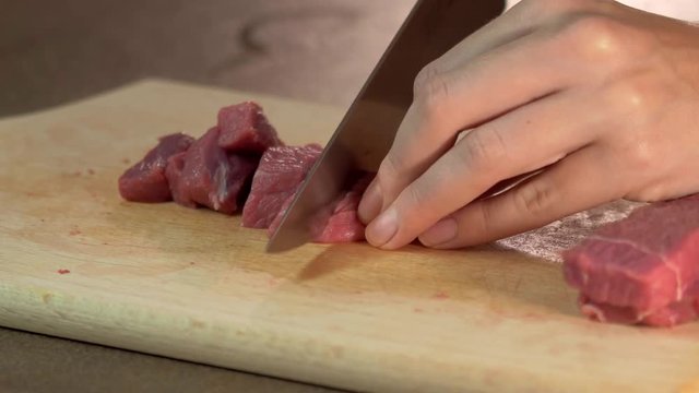 Woman cutting beef with a knife at home