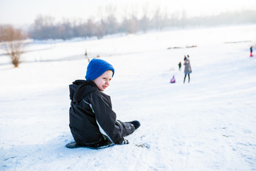 Fototapeta na wymiar Cute boy is sitting on snow