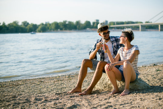 Hipsters are having drink on shore