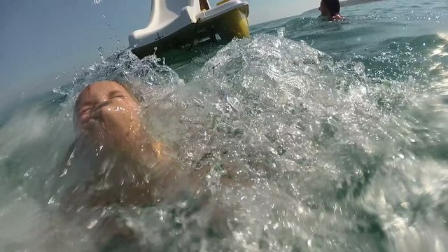 girl on pedal boat pulls off the hill into the sea, view from water
