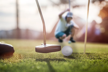 putter hit a golf ball follow through the hold target on the green with golfmate in measuring line for next putting winner