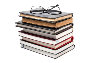 A stack of books with eyeglasses on a white background.