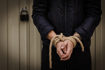 Male hands tied with a rope.