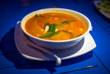 Tom Yum Kung (Thai famous soup with shrimp or prawn and coconut milk) on in white bowl isolated on table, Food of Thailand