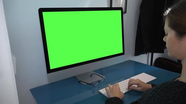 Woman Typing On Computer Keyboard, Green Screen Dolly Shot. Young woman typing on a computer keyboard in the office. Green screen footage Dolly shot