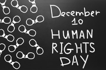 Human rights concept: handcuffs and the text: Human rights day written on blackboard.