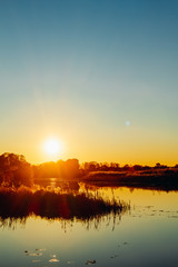 Sunset on the river bank with reflection in the water