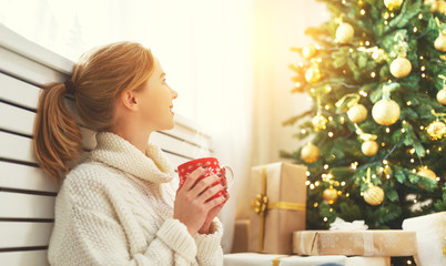 happy woman with a mug of tea near Christmas tree