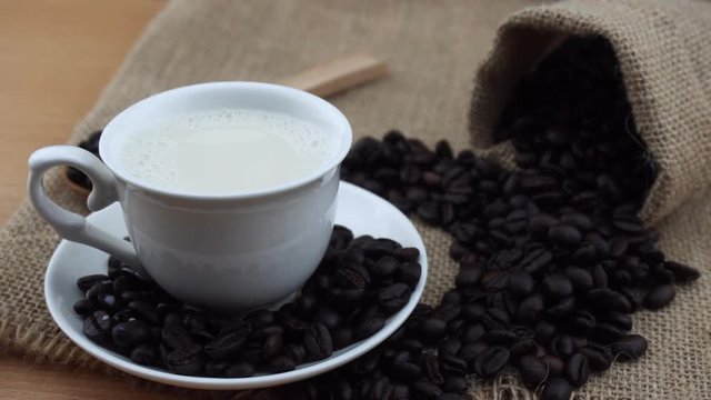 milk in a coffee cup with coffee beans on sack bag