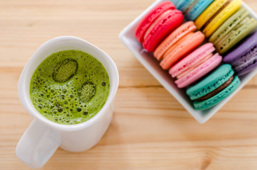 Colorful macaroons and green tea on wooden table background
