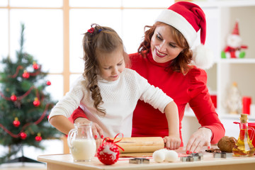 Adorable little girl and mother baking Christmas cookies