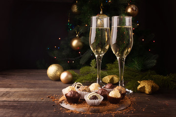 Two glasses with champagne and chocolate sweets from different types of chocolate on the New Year's...