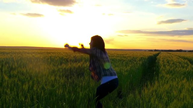 Young woman jumping on a yellow wheat field on a sunset background. The concept of freedom. Happy woman outdoors. Harvest. Wheat field at sunset.
