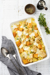 Casserole from chicken meat, pumpkin, pasta ,thyme, cheese and béchamel sauce in ceramic form on light concrete or stone background. Selective focus. Top view. Copy space.