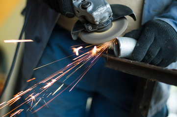 A man is working a metal pipe with a tool for cutting metal