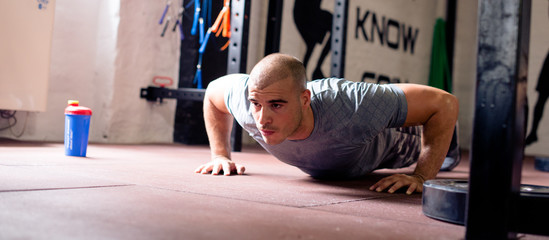 Man in gym doing push ups, panorama