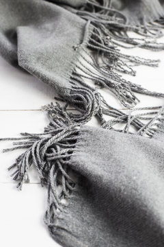 Background texture of the crumpled gray winter fashionable female scarf. On a white wooden table