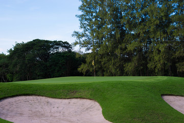 A lush green golf course under the blue sky.