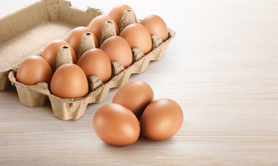 Carton egg box with eggs on a wooden background.