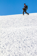 Naklejka na ściany i meble Man is snowshoe hiking through deep snow on sunny day