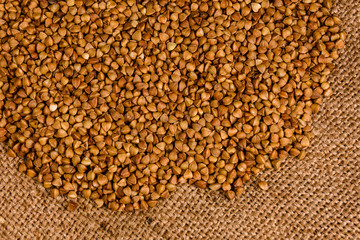 Pile of the raw buckwheat on sackcloth. Top view