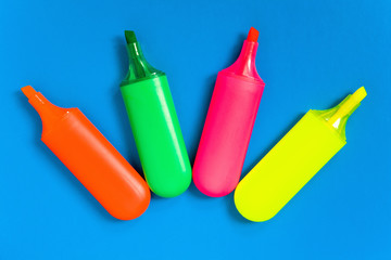 Multicolored markers lie on a blue sheet of paper.