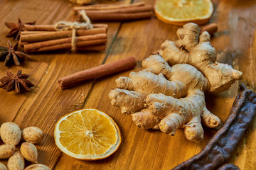 A big piece of ginger on wooden brown background. Ingredients for mulled wine: dried fruits, orange, ginger, cinnamon, anise stars and nuts. Close up view
