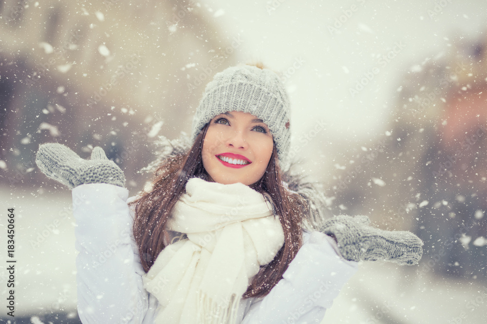 Wall mural beautiful smiling young woman in warm clothing. the concept of portrait in winter snowy weather