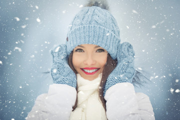 Beautiful smiling young woman in warm clothing. The concept of portrait in winter snowy weather