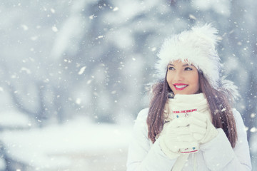 Beautiful smiling young woman in warm clothing with cup of  hot tea coffee or punch. The concept of portrait in winter snowy weather