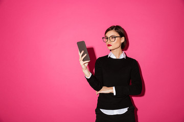 Young confident lady in black pullover using smartphone isolated