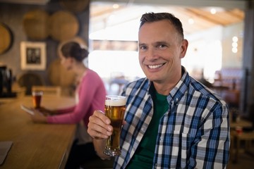 Portrait of smiling man having glass of beer at bar counter