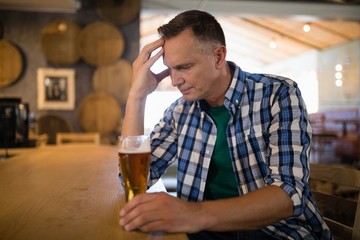 Worried man sitting at bar with glass of beer
