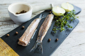 Prepared fresh salted herrings on a stone board.
