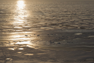 Winter nature landscape. The frozen sea in the rays of the setting sun
