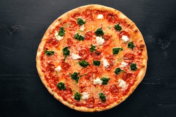 Neapolitan Pizza. Spinach, gorgonzola cheese, sausage salami. On a wooden background. Top view.