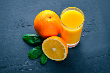 Orange fresh juice and oranges on a wooden surface. Top view. Free space for text.