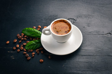 A cup of coffee and coffee beans on a wooden background. Top view. Free space for text.